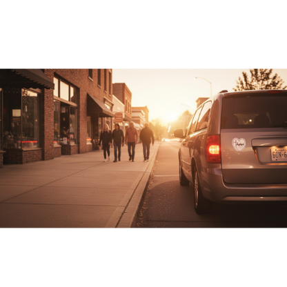 Agapē heart-and-cross magnet on parked vehicle near storefronts at golden hour